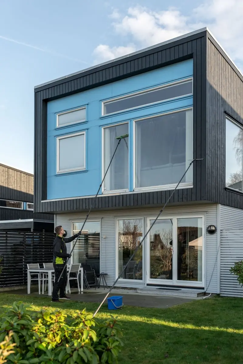Ansatt i Elite Vinduspuss som vasker vinduene på en bolig.