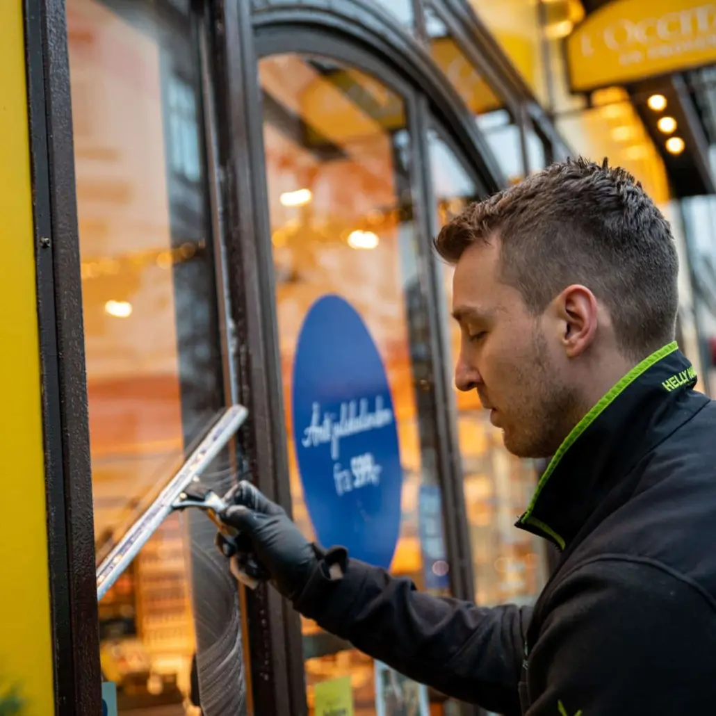 Ansatt i Elite Vindupuss som vasker butikkvinduer.